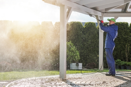 \Worker with a pressure washer cleaning the roof of a Patio House.